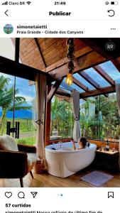 a woman in a bath tub in a room with a window at Chalé Envidraçado Recanto Verde dos Canyons in Praia Grande