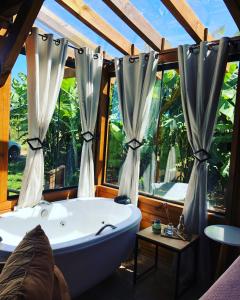 a bathroom with a tub and a large window at Chalé Envidraçado Recanto Verde dos Canyons in Praia Grande