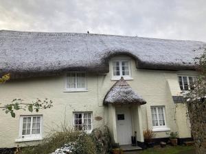 une maison blanche avec un toit de chaume dans l'établissement Little Reeds, à Bovey Tracey