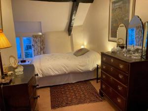 a bedroom with a bed and a dresser and a window at Little Reeds in Bovey Tracey