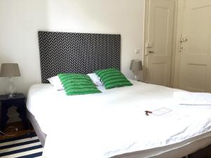 uma cama branca com duas almofadas verdes em The Color Hostel em Lisboa
