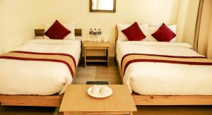 Habitación de hotel con 2 camas y mesa en HOTEL LUMA INN, en Pokhara