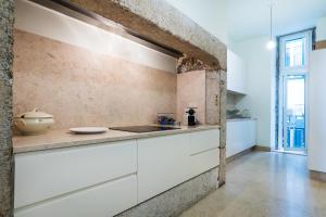 a kitchen with white cabinets and a brick wall at Santa Justa Prime Guesthouse in Lisbon +37 photos
