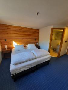 a bedroom with a large white bed with a wooden headboard at Las Bravas Lodge in Las Trancas