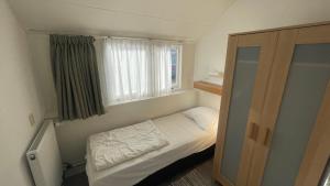 Habitación pequeña con cama y ventana en Strandhuis Everts, en Egmond aan Zee