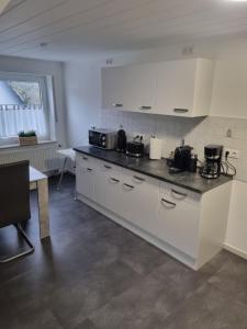 a kitchen with white cabinets and a counter top at Ferienwohnung am Fuße des Eggegebirges in Bad Driburg