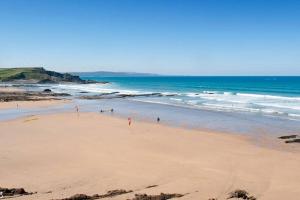 a beach with people walking on the sand and the ocean at Huge 7 bed hse for large groups close by the beach in Bude