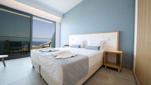 a bedroom with a large bed and a large window at Panorama Village Hotel in Agia Pelagia