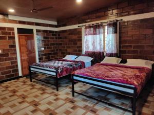 a room with two beds and a brick wall at Green Hills Farm And Guest House in Masinagudi