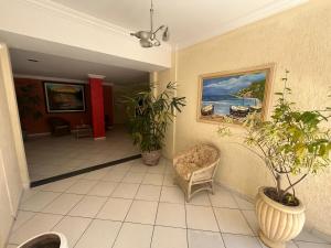 korytarz z roślinami, krzesłem i obrazem w obiekcie Residencial nautilus 303 w mieście Balneário Camboriú