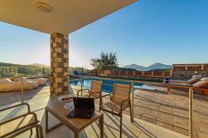 a laptop on a table on a balcony with a pool at Asfendamos Villas in Zonianá