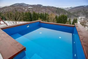 una piscina blu con montagne sullo sfondo di Pensiunea Cascada a Nemesi
