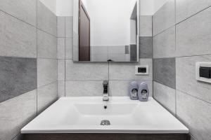 bagno con lavandino bianco e specchio di MilanRentals - Vigliani Apartments a Milano