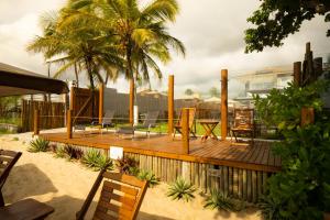 a wooden deck with chairs and a table and palm trees at Village Someday in Arraial d'Ajuda
