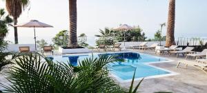 a swimming pool with tables and chairs and the ocean at Maresía Village in Los Realejos