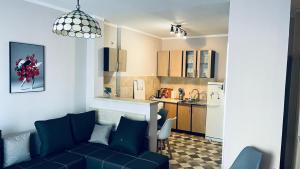 a living room with a blue couch and a kitchen at Majdini Clock Tower Apartman in Podgorica