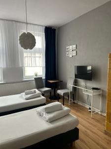 a room with two beds and a desk and a television at Hostel Octopus Gdańsk in Gdańsk