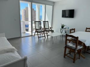 a bedroom with a bed and chairs and a tv at Ninfas Plaza in Puerto Madryn