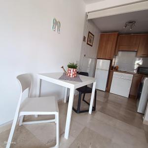 uma cozinha com uma mesa branca e uma cadeira branca em Apartment Las Arenas - Las Casas de Aron em Caleta De Fuste