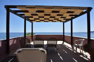a screened porch with chairs and the ocean in the background at Horizon Beach Hotel in Plakias