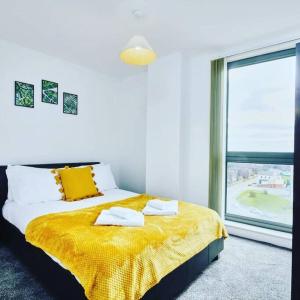 um quarto com uma cama com um cobertor amarelo e uma janela em Yorksha Luxury Apartments Leeds em Leeds