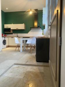 a kitchen with a table and chairs and a green wall at Le loft Rousseau in Dijon