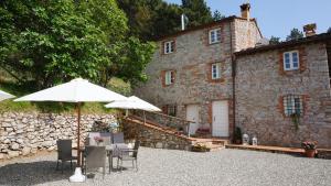 a house with a table and umbrella in front of it at Agriturismo le Vallilunghe in Lucca