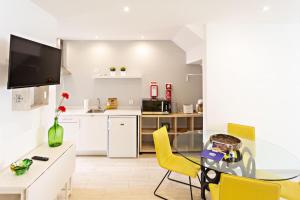 uma cozinha e sala de jantar com uma mesa de vidro e cadeiras amarelas em Apartamentos da Cidade em Tavira