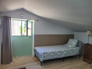 Schlafzimmer mit einem Bett und einem Fenster in der Unterkunft Gîte l'atelier de Phil et Delfe in Sainte-Cécile-les-Vignes