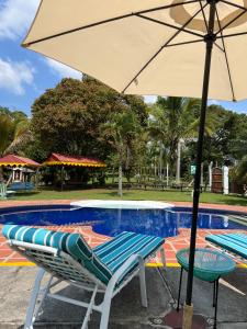 um par de cadeiras e um guarda-sol ao lado de uma piscina em Casa Lemar em Quimbaya