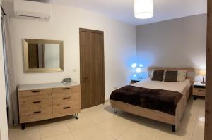 een slaapkamer met een bed, een dressoir en een spiegel bij Spinola Bay Apt - Beatiful 3-Double Bed apt near beach in Prime Location in St Julian's