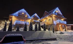 a house covered in christmas lights in the snow at Osada Jaworki B&B in Jaworki