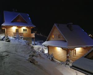 two houses covered in snow with lights on them at Osada Jaworki B&B in Jaworki