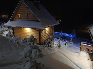 a cabin in the snow at night with lights at Osada Jaworki B&B in Jaworki