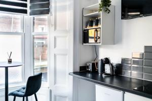 a kitchen with white cabinets and a black counter top at Chic Studio Apartment in Prime London Location in London