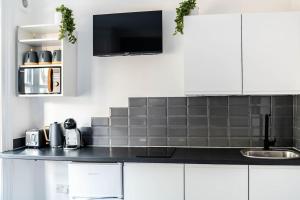 a kitchen with white cabinets and a black counter top at Chic Studio Apartment in Prime London Location in London