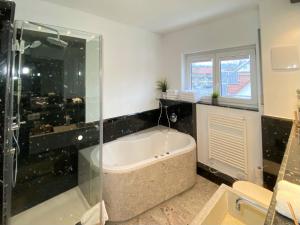 a bathroom with a tub and a glass shower at 4 Zimmer Apartment, 125 qm, ruhig und zentrumsnah, max 5 Pers, Dachterasse, Garage, 1000 MBit in Böblingen