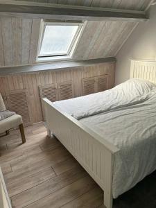 1 dormitorio con cama blanca y ventana en Apartment at the Beach en Noordwijk