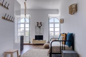 a living room with a bed and two windows at Apartamentos do Rio in Tavira