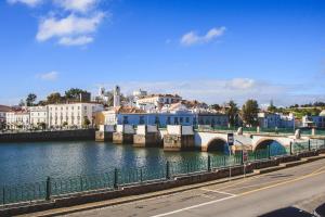 a bridge over a river with buildings in the background at Apartamentos do Rio in Tavira