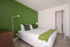 een slaapkamer met een groot bed met een groene muur bij CASASUPERTUBOS® Apart 9-14 in Peniche