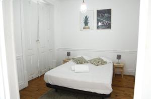 a white bedroom with a bed and two tables at Original Lisbon Guesthouse in Lisbon