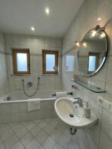een badkamer met een wastafel, een bad en een spiegel bij Haus Wiesenblick in Thurmansbang