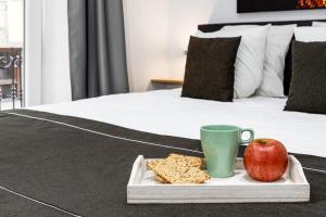 a tray with an apple and a cup on a bed at Pinzon Studios & Penthouse in Alicante