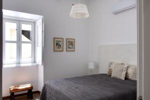 a white bedroom with a bed and a window at Apartamentos do Rio in Tavira