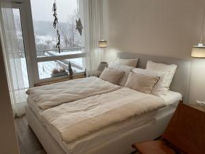 uma grande cama branca num quarto com uma janela em HEARTH HILL VIEW APARTMENT em Ustroń