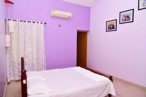 TellicherryにあるBella Apartmentsの紫の壁のベッドルーム1室(ベッド1台付)