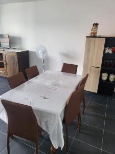 a dining room table with a white table cloth and chairs at Cap Au Soleil in Saint-Pierre