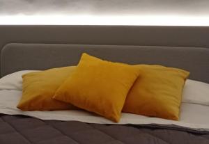 2 cuscini gialli posti sopra un letto di Narciso boutique apartment ad Acireale