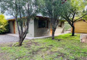 a house with three trees in front of it at Fly Fishing Cabin, River Coast. in Los Helechos